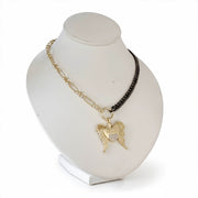 Necklace with angel wing and heart pendant on a white stand