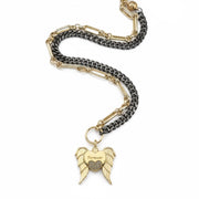 Necklace with gold and black chain and angel wing charm on a white background