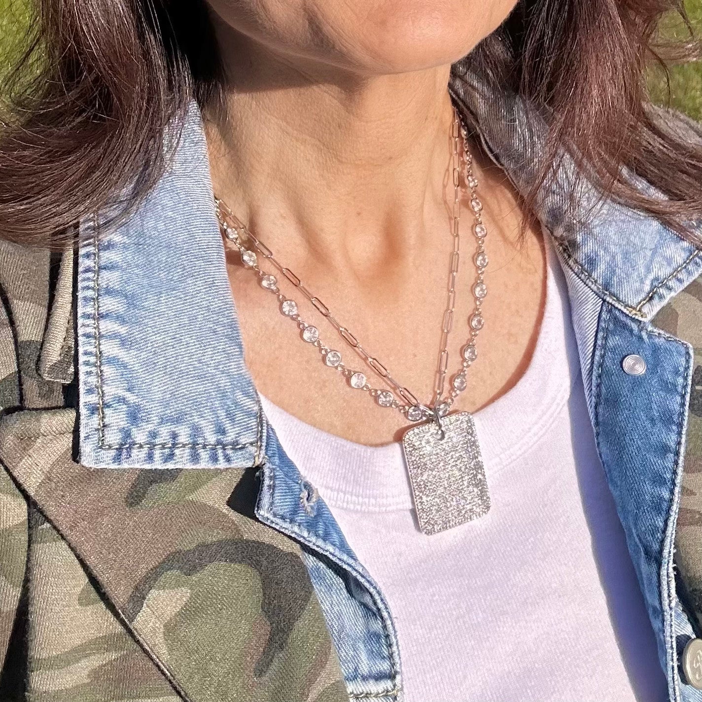 Model wearing gold Gabby Diamond Dog Tag Necklace layered over denim jacket