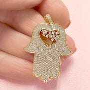 close up of gold glam hamsa charm love lisa jewelry with crystal accents and heart cutout