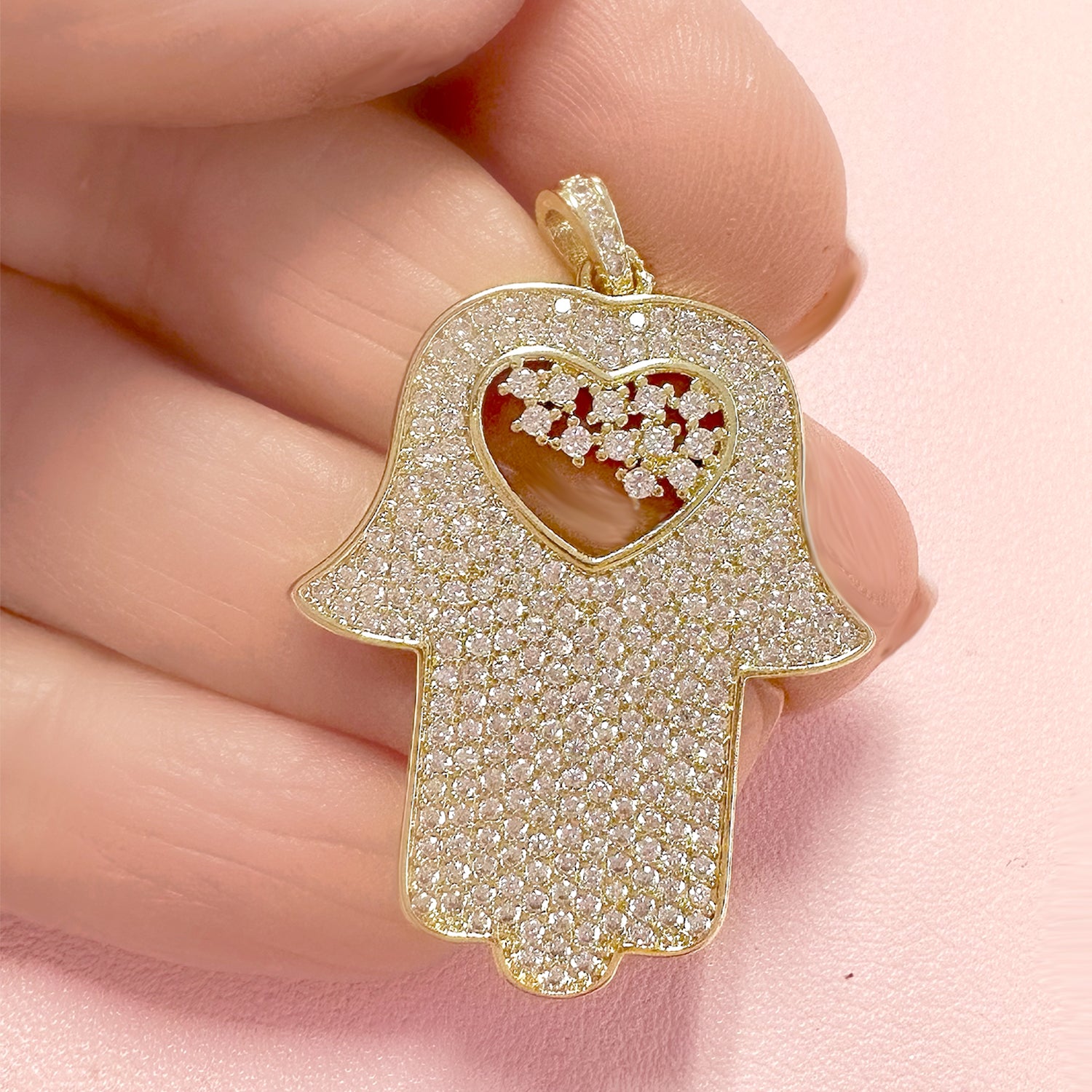 close up of gold glam hamsa charm love lisa jewelry with crystal accents and heart cutout