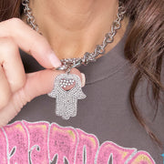 Model holding Glam Hamsa Charm close to neckline