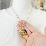 hand holding gloria evil eye enamel charm love lisa jewelry colorful pavé pendant symbol of luck and intuition