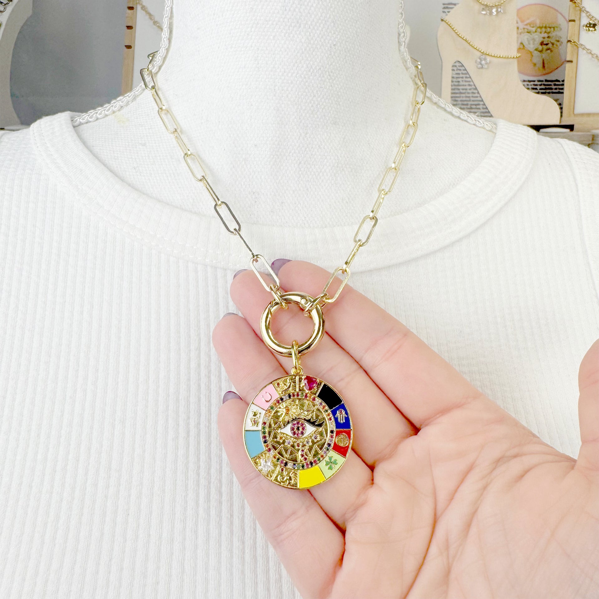 hand holding gloria evil eye enamel charm love lisa jewelry colorful pavé pendant symbol of luck and intuition