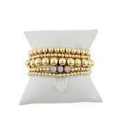 Gold stack of beaded bracelets with a heart charm 