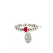 A silver beaded stretch bracelet featuring a faceted red gemstone and a dangling silver Miraculous Medal charm, shown on a plain white background.