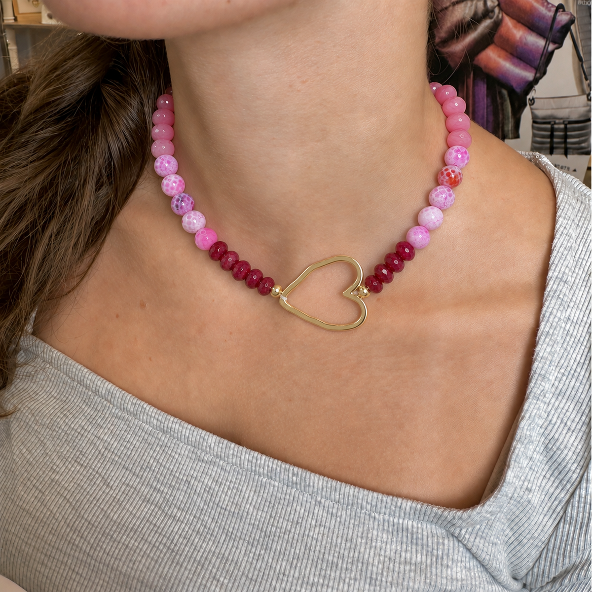 Love Lisa Hailey Breast Cancer Awareness Necklace worn at the neckline with pink gemstone beads and an oversized polished gold-tone open heart centerpiece