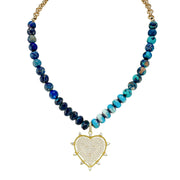 A pave necklace featuring a heart-shaped pendant with a golden frame, adorned with navy blue crystal beads and turquoise accents.