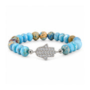 ove Lisa Hamsa Mixed Gemstone Beaded Bracelet in Light Blue with faceted blue rondelles, blue and tan patterned round gemstone beads, silver-tone accents, and a sparkling pavé CZ Hamsa centerpiece