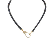 A navy blue beaded necklace with a gold pave clasp.