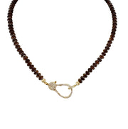 A brown beaded necklace with a gold pave clasp.