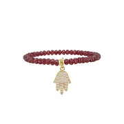 Bracelet with red beads and gold Hamsa hand charm on a white background