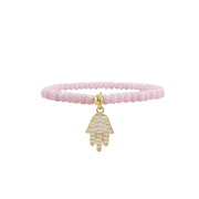 Pink beaded bracelet with a gold Hamsa charm on a white background