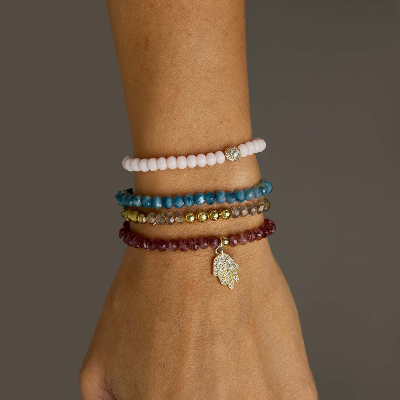 Stack of beaded bracelets on a wrist with a neutral background
