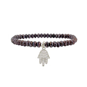 Bracelet with dark beads and a silver Hamsa hand charm on a white background