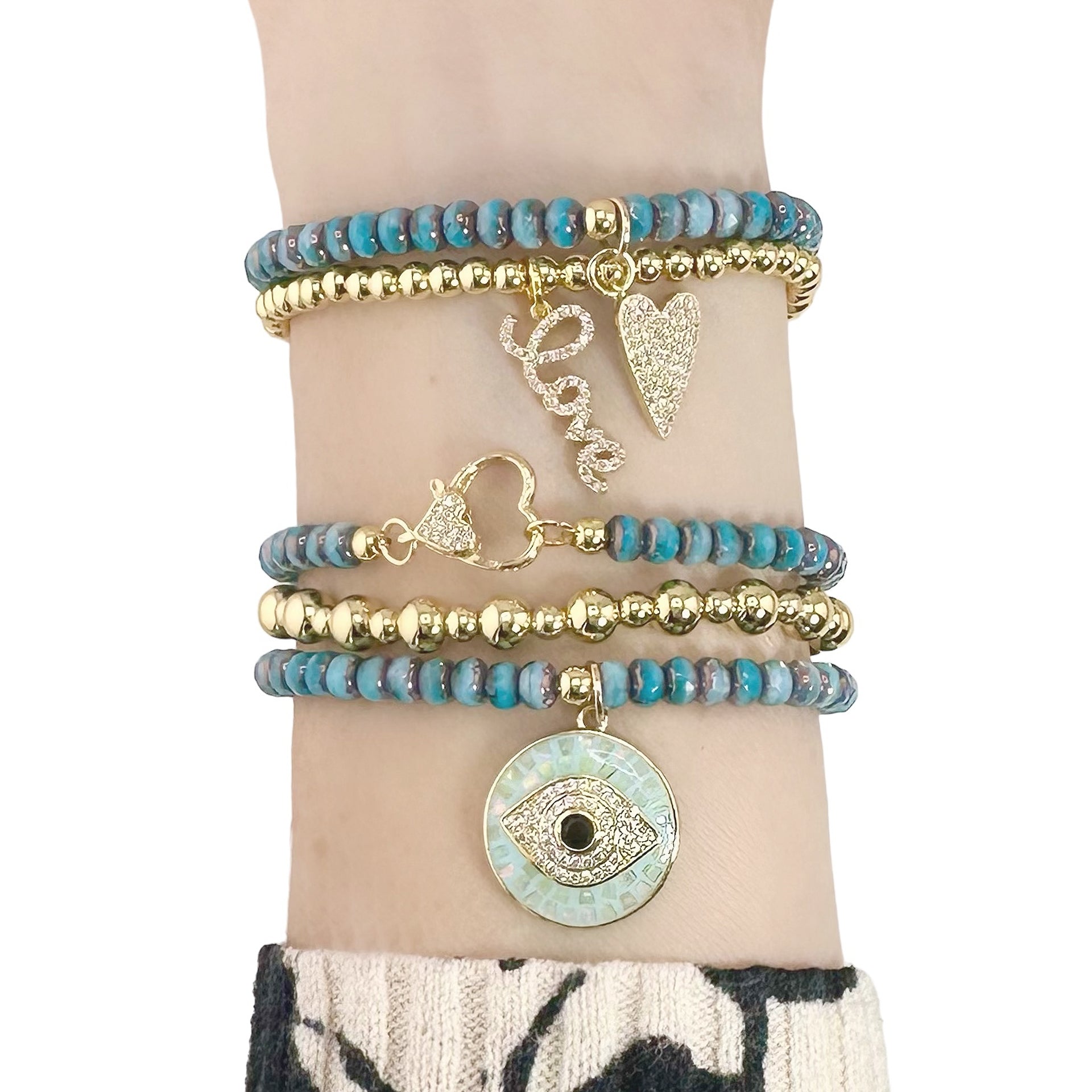 Multiple bracelets with blue beads and gold accents on a wrist against a white background