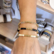 Hand wearing three beaded bracelets on a blurred background