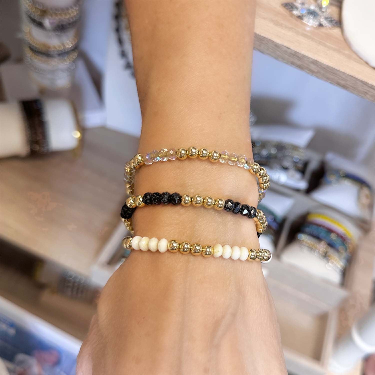 Hand wearing three beaded bracelets on a blurred background