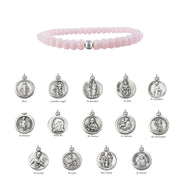 Pink beaded bracelet with silver religious charms on a white background