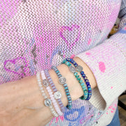 Love Lisa layered harper subliminal saint bracelets worn stacked on wrist with multiple saint medallions
