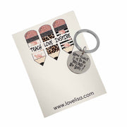 A keychain with a message 'How sweet it is to be taught by you' on a background that includes a graphic of chalk and floral design. The keychain is attached to a metal ring and comes in a small, adorned pouch.