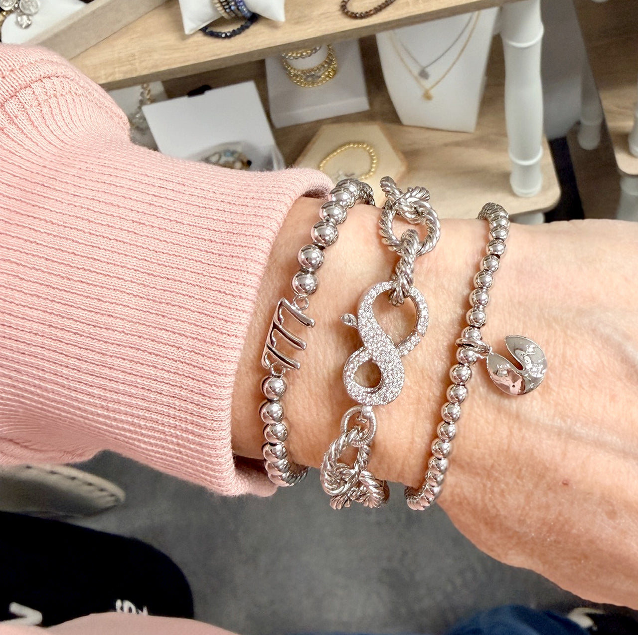 silver infinity clasp chain bracelet stacked on wrist with love lisa bracelets showing textured rope chain and crystal infinity clasp