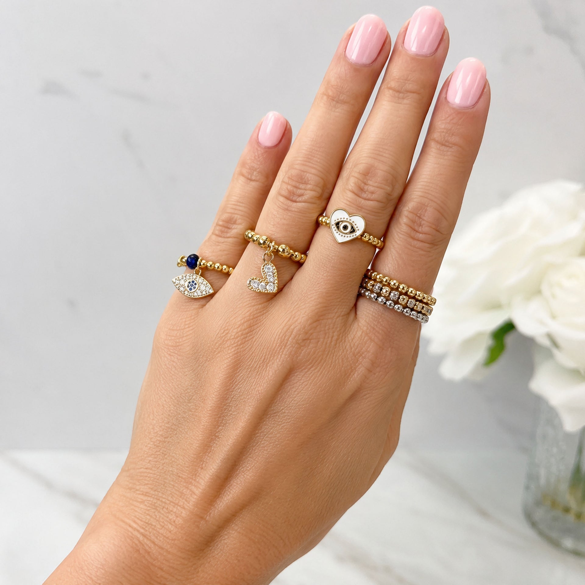Love Lisa Isabella Enamel Evil Eye Heart Stretch Ring worn on hand with colorful evil eye heart rings and gold beaded stretch rings