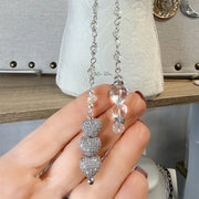Close view of triple pavé heart drop and clear AB crystals on long crystal lariat necklace