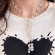 Long crystal lariat necklace layered over sweater with shimmering heart drop and silver tone chain