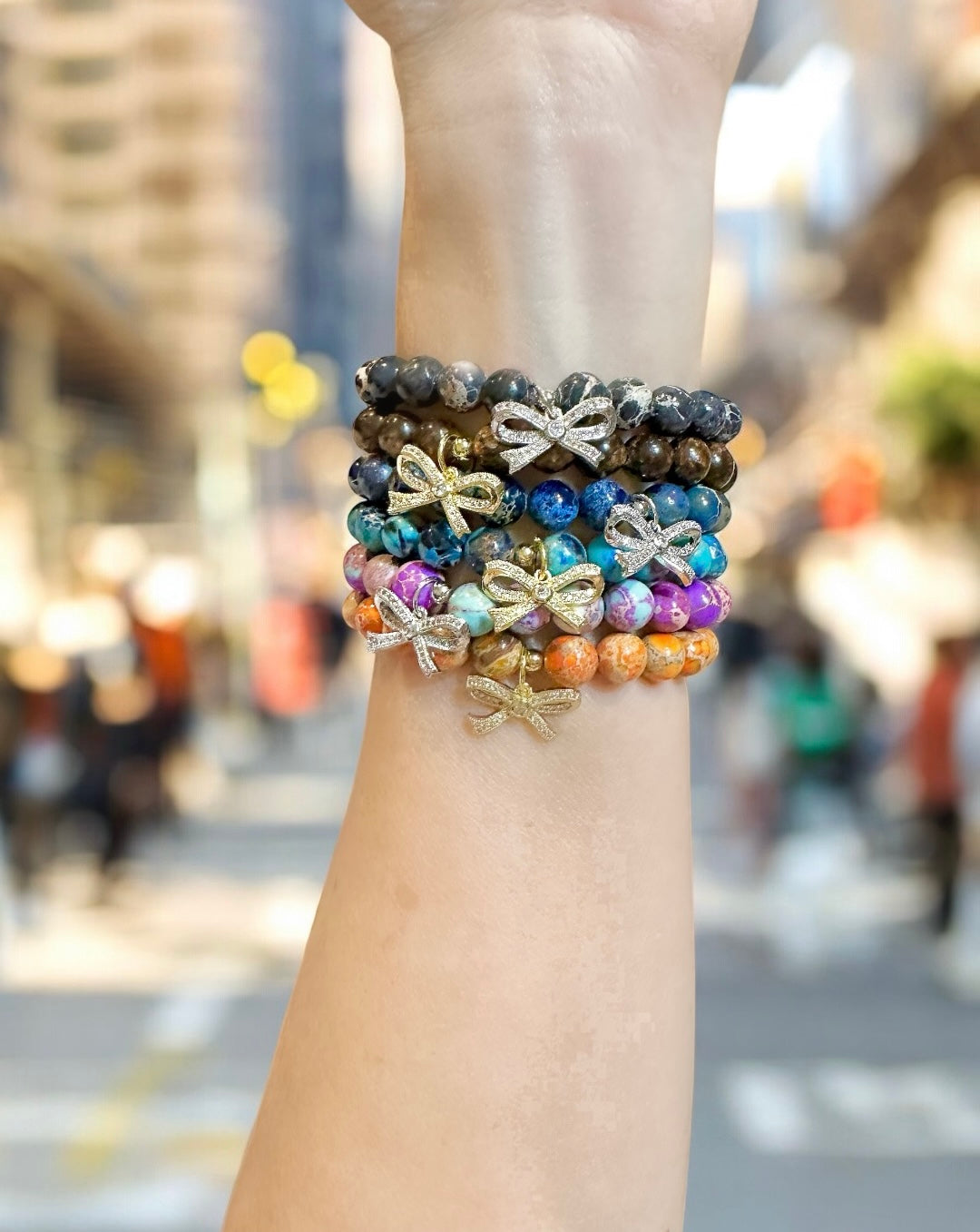 love lisa gemstone stack featuring isla sea sediment jasper bow bracelet worn on wrist in outdoor street style photo