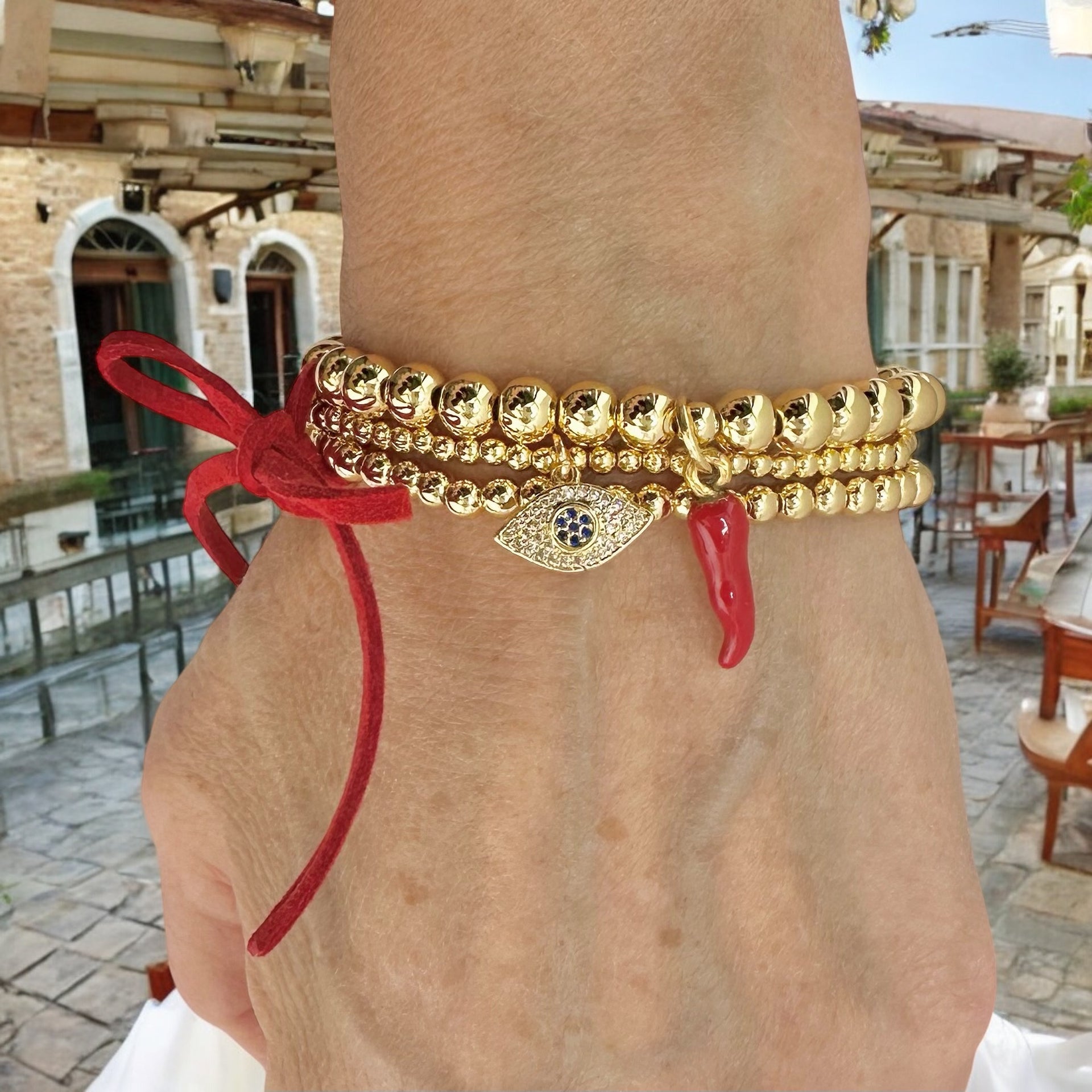 Evil eye and italian horn in red charm on this three stack of beaded bracelets on a model in Sorrento Italy