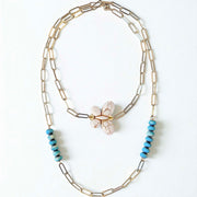 Necklace with butterfly charm and turquoise beads on a white background double wrapped around