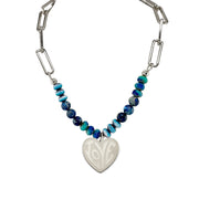 A blue beaded necklace with a heart-shaped pendant, featuring a silver chain and a lobster clasp.