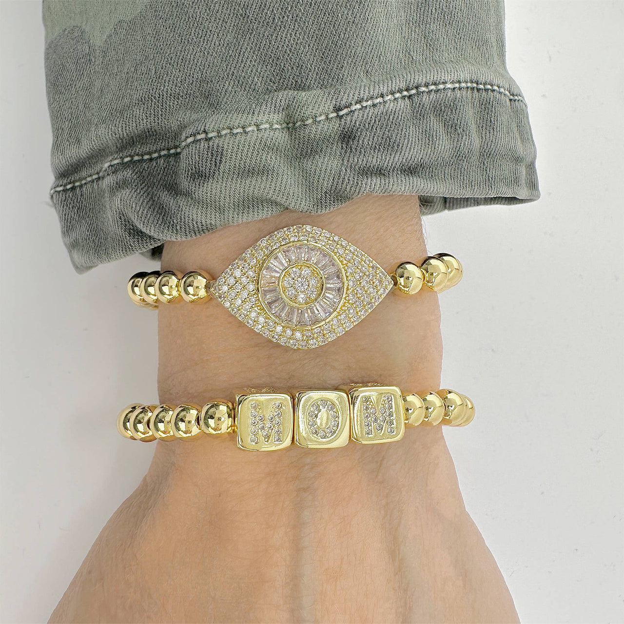 love lisa laurel luxe evil eye bracelet gold beaded bracelet stacked with other protection bracelets on wrist