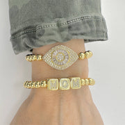love lisa laurel luxe evil eye bracelet gold beaded bracelet stacked with other protection bracelets on wrist