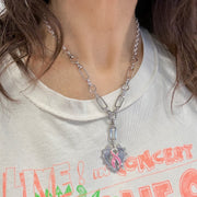 Love Lisa Layla Breast Cancer Awareness Pink Ribbon Necklace worn with Y-link chain, spiked heart pendant, and pink enamel ribbon charm