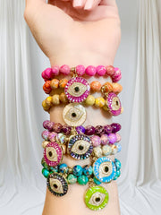 Love Lisa Lena Breast Cancer Awareness Evil Eye Bracelet worn in a colorful wrist stack with pink gemstone beads and a large sparkling evil eye charm