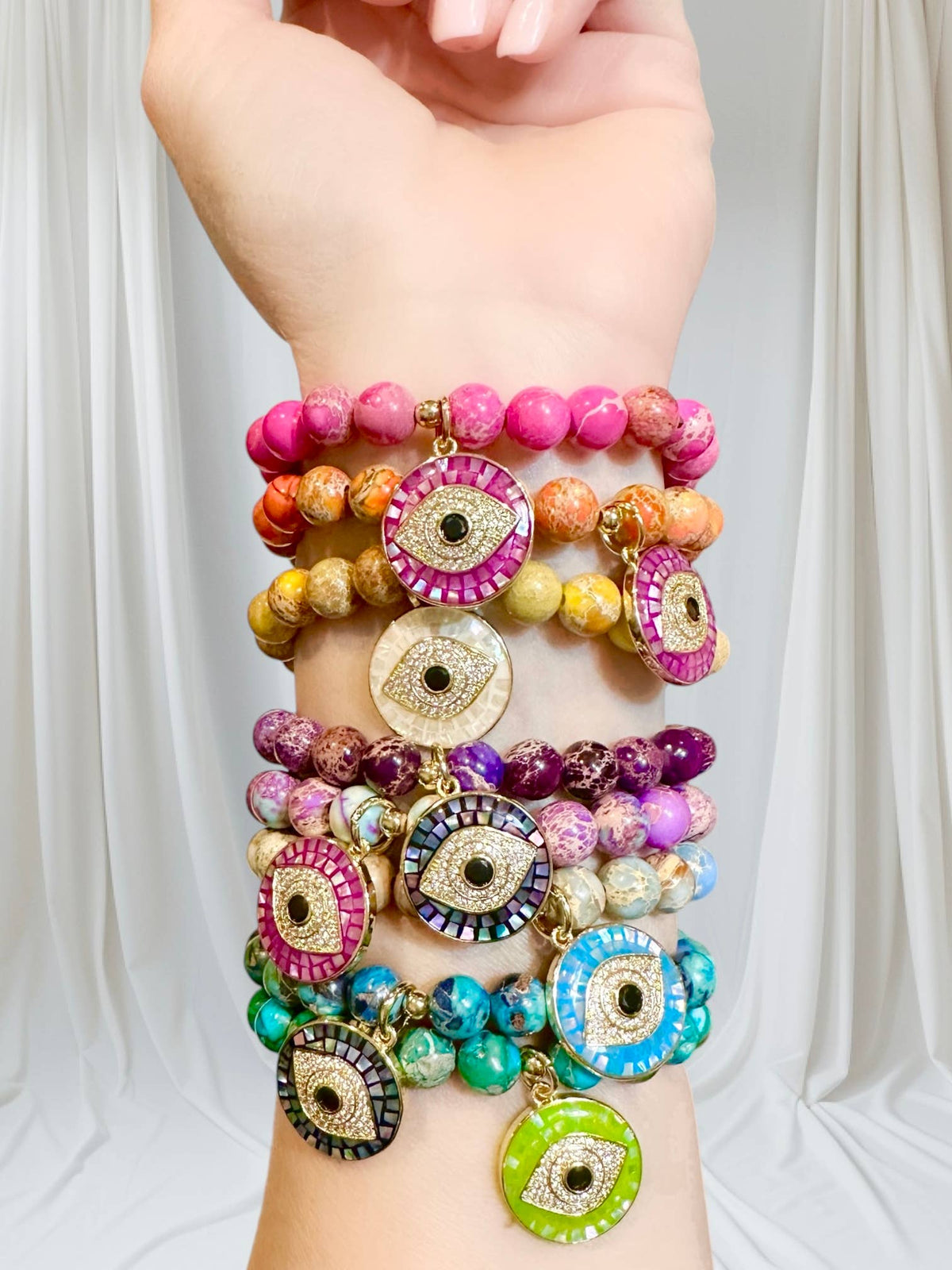Love Lisa Lena Breast Cancer Awareness Evil Eye Bracelet worn in a colorful wrist stack with pink gemstone beads and a large sparkling evil eye charm
