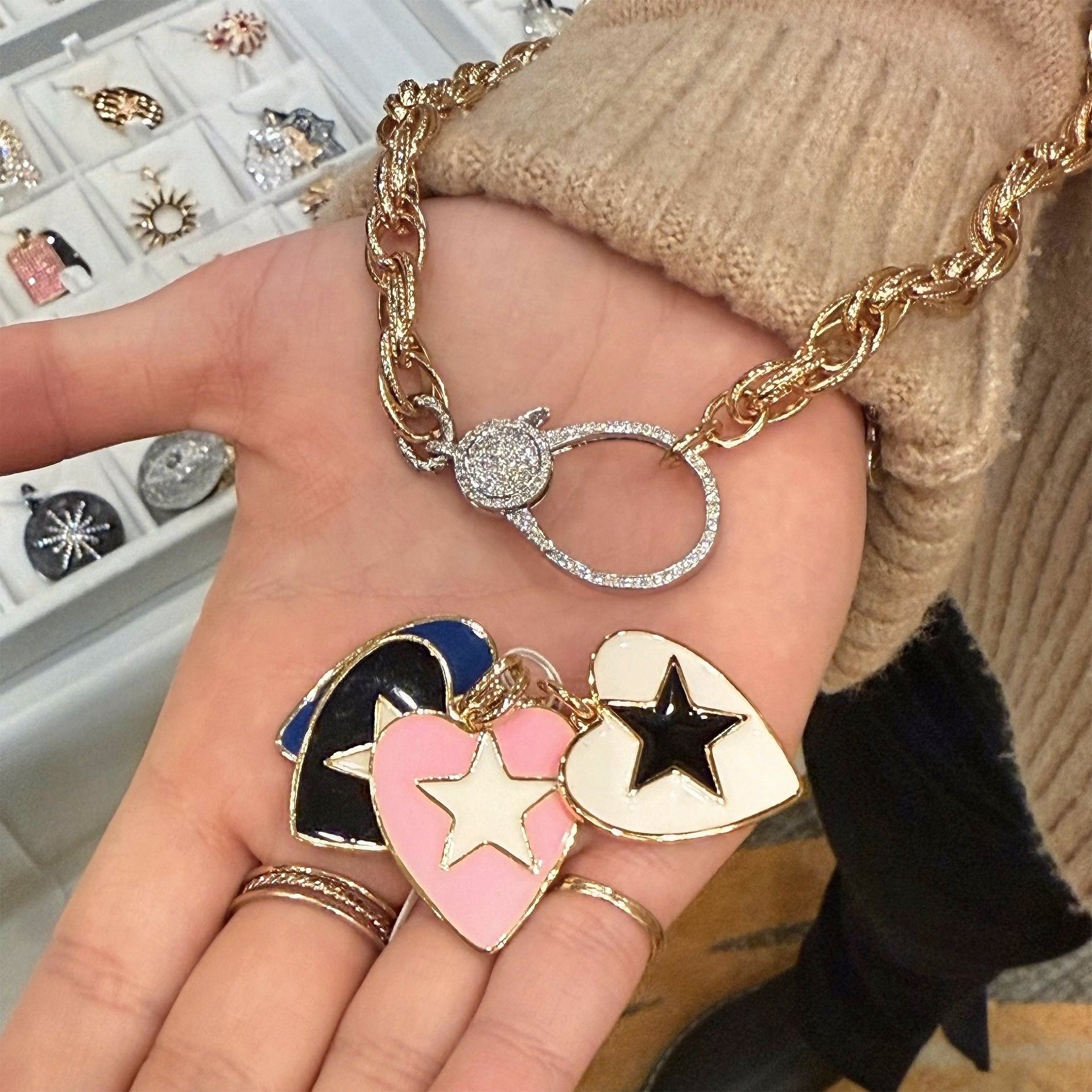 love lisa leslie starlit glowing enamel heart charms in black royal blue white and pink held in hand on bracelet