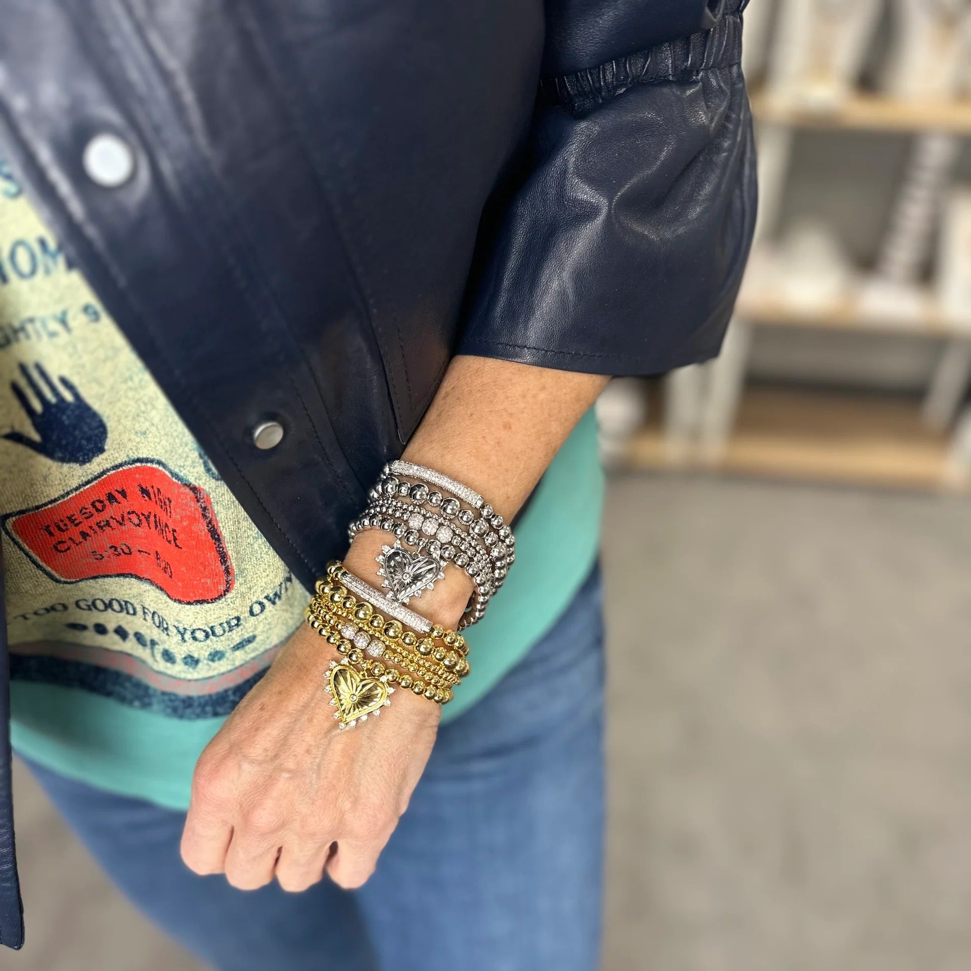 Person wearing multiple bracelets on a wrist with a blurred background