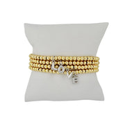 gold lila bubble letter initial bracelet displayed on jewelry pillow showing polished beaded design