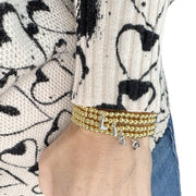 wrist wearing gold lila bubble letter initial bracelet styled with a cozy sweater for everyday look
