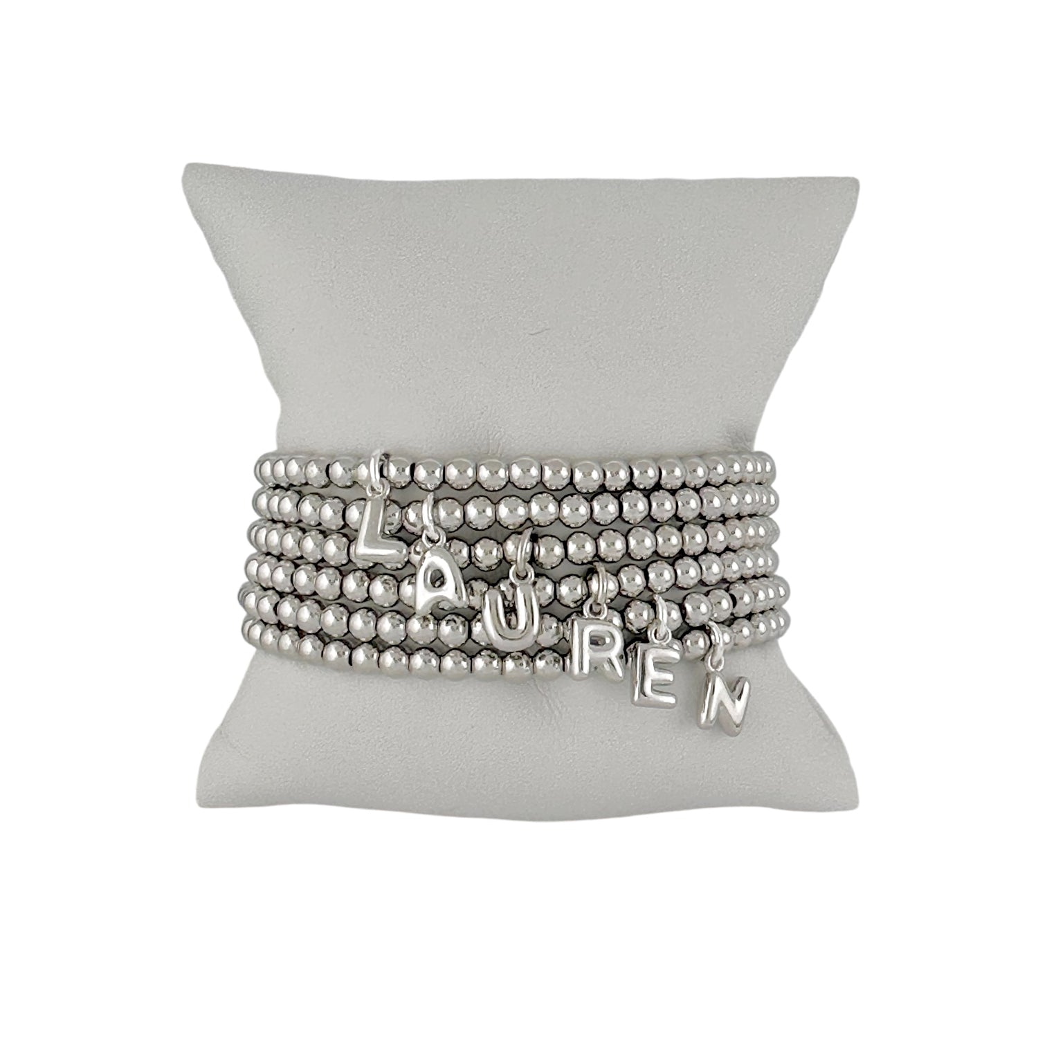 silver lila bubble letter initial bracelet displayed on jewelry pillow showing polished beaded design