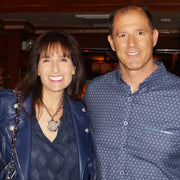 woman wearing LOVE coin necklace with silver spike pendant standing next to man