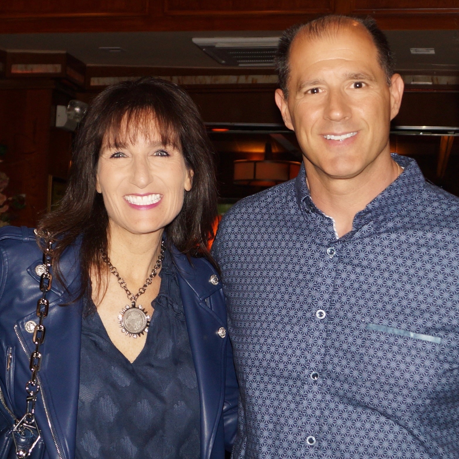woman wearing LOVE coin necklace with silver spike pendant standing next to man
