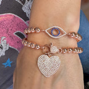 Close-up of two bracelets on a wrist, one with a heart charm and the other with an eye design.
