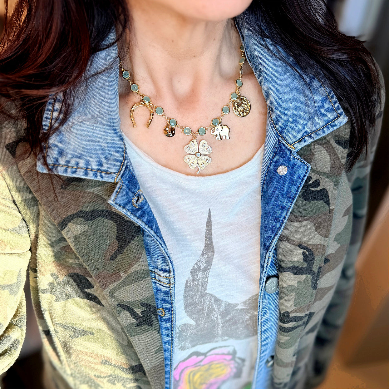Lucky clover green stone necklace styled with denim jacket highlighting gold charms and soft green stones