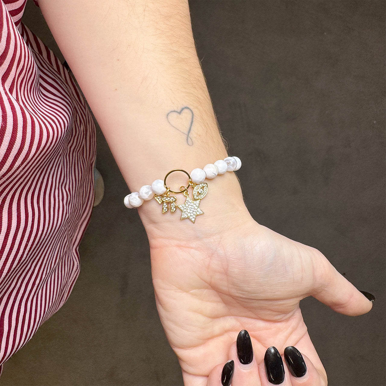 white fire agate star of david gemstone bracelet with chai and evil eye charm trio on wrist
