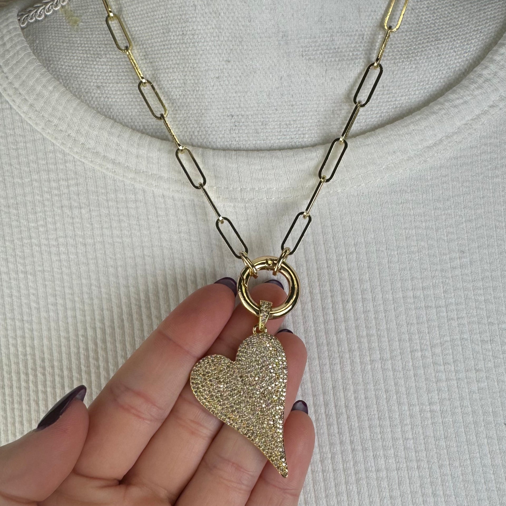 Gold slanted heart charm with shimmering pavé crystals in hand