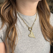 Gold slanted heart charm with shimmering pavé crystals on model